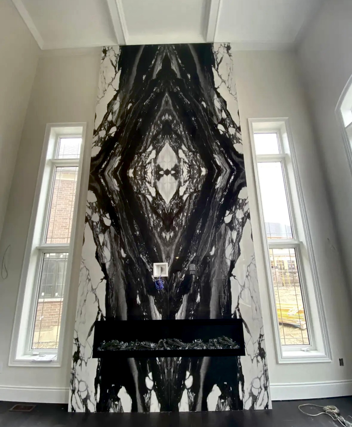 Two-storey book-matched Calacatta Viola marble fireplace feature wall with linear gas insert, installed by Goldstein Construction