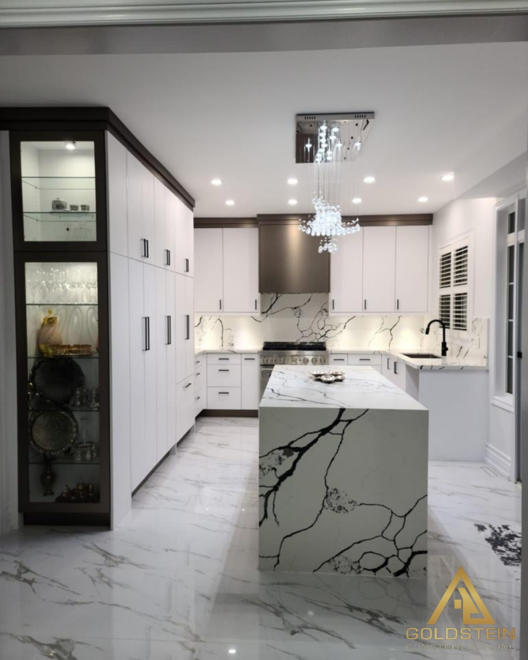 Luxury kitchen with waterfall marble island and matching backsplash.