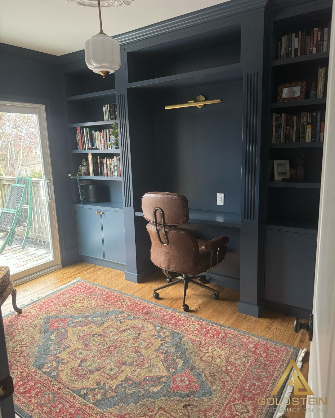 Deep-blue home office with floor-to-ceiling millwork and leather chair