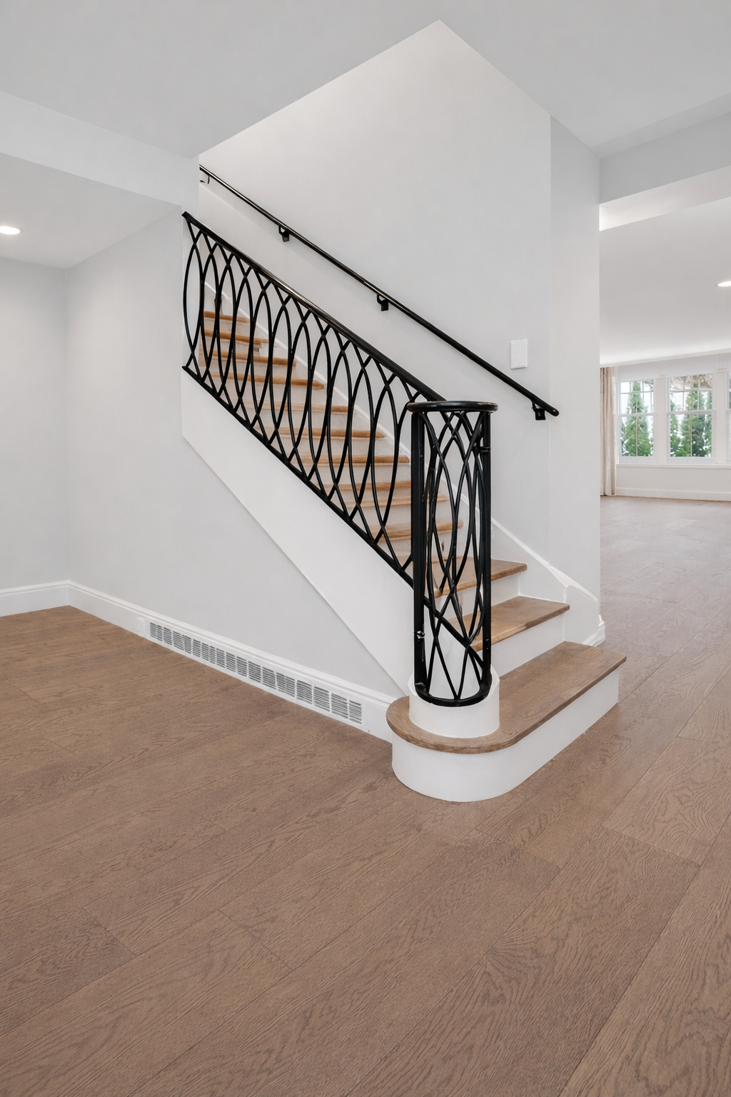 Bright entry with custom black iron staircase railing and light wood steps.