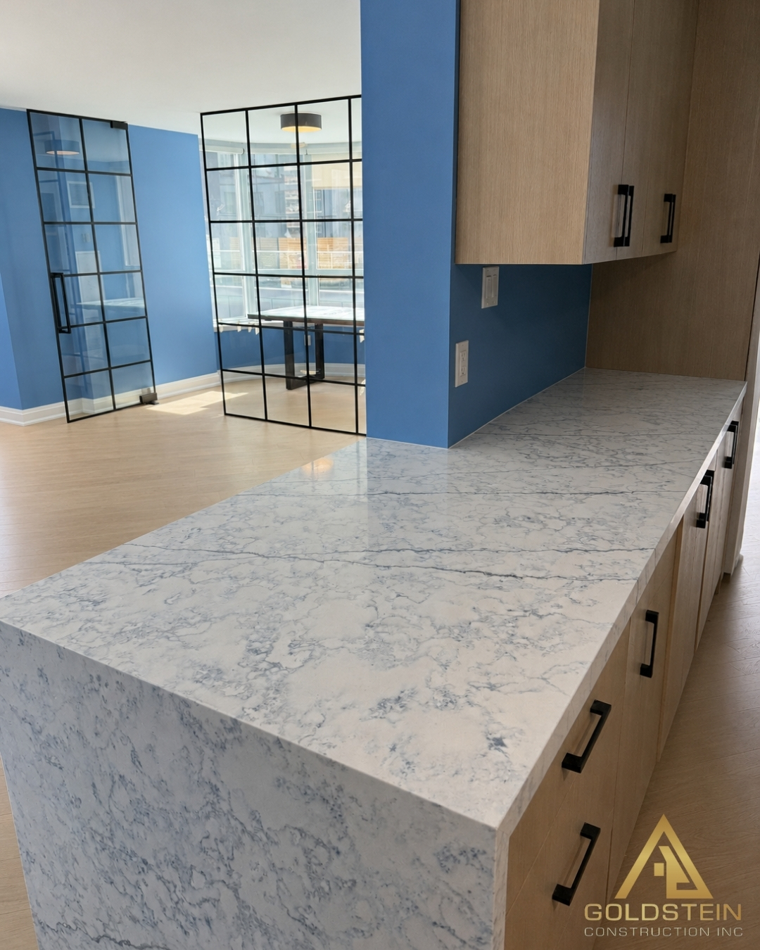 Toronto condo kitchen with waterfall marble island and steel-framed glass partitions