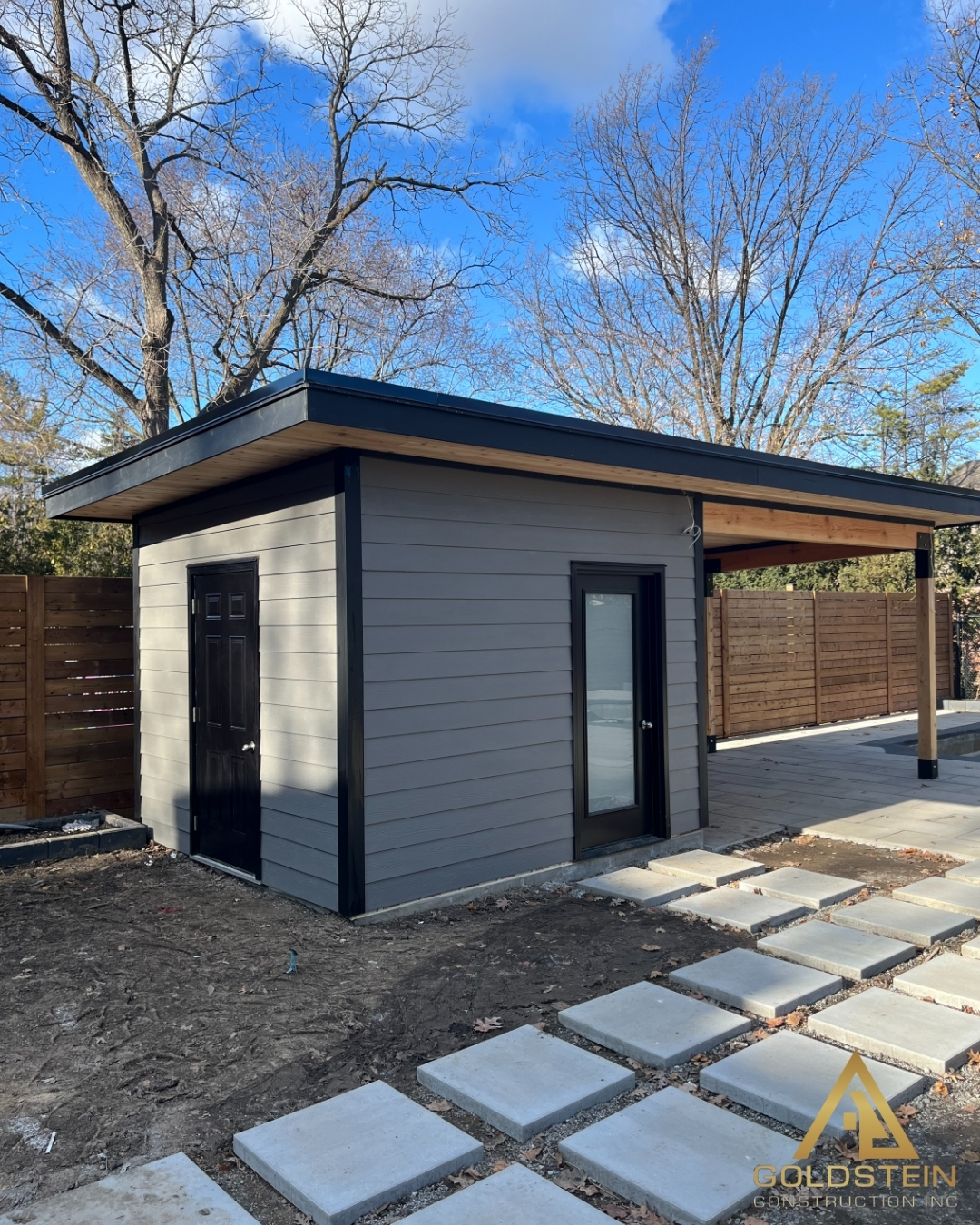 Modern grey backyard cabana with cedar-lined covered porch