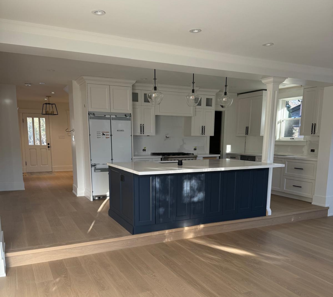 Bright open-concept kitchen with navy island and white shaker cabinetry