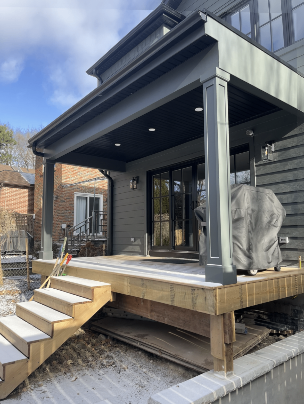Covered rear deck addition with steps and dark exterior finishes.