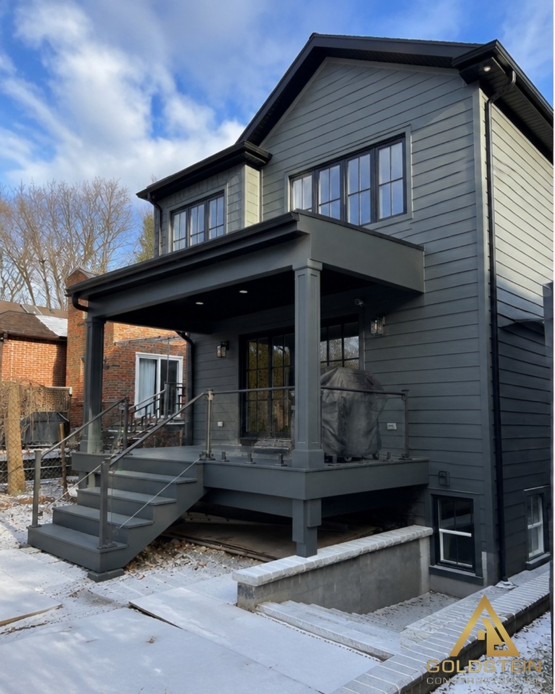 Two-storey home addition with dark siding, black windows and covered rear deck