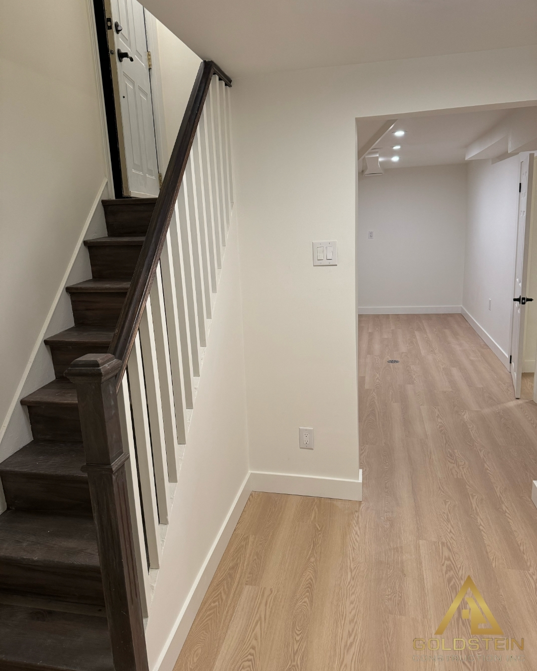 Bright rebuilt basement with light hardwood floors and refinished staircase