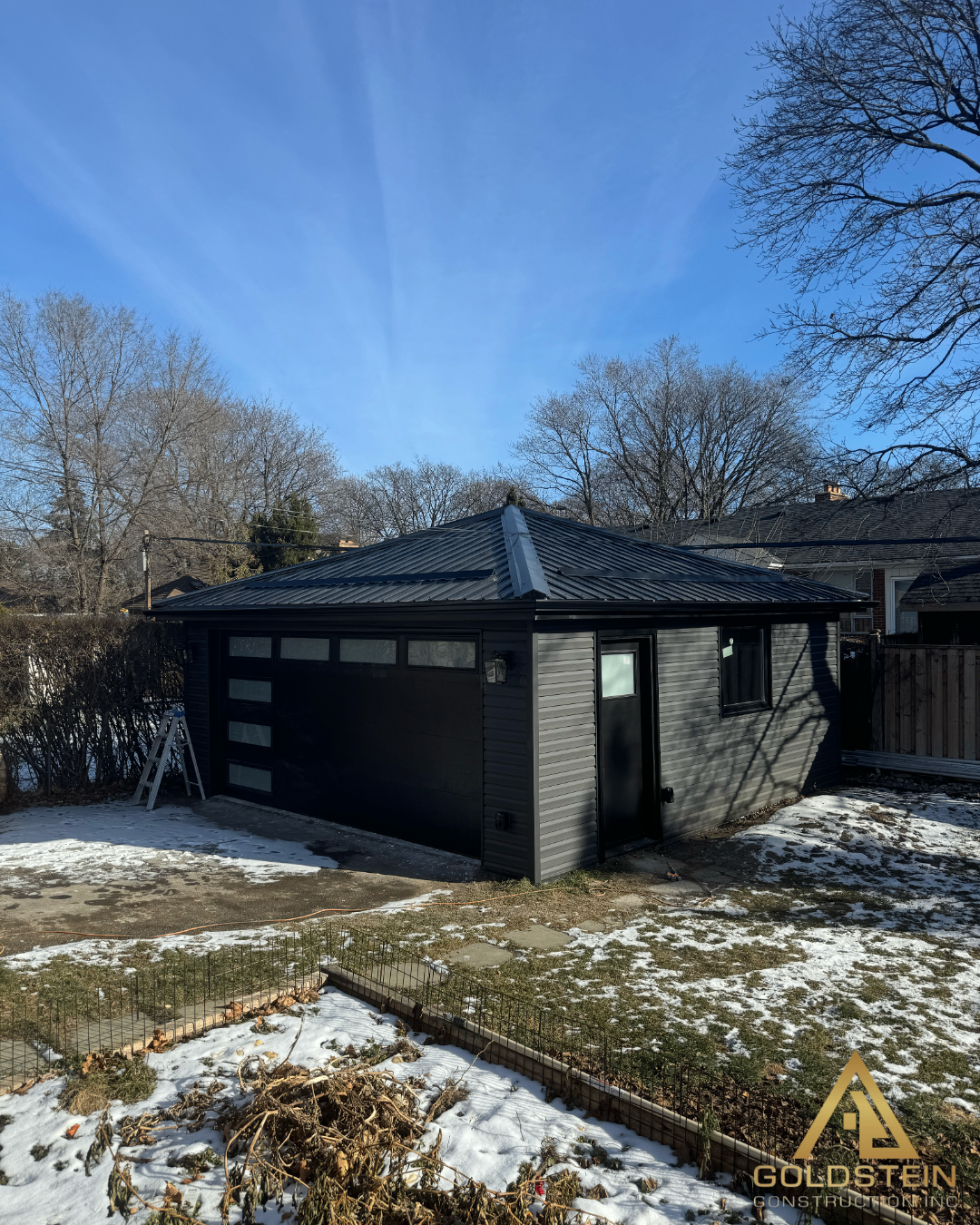 Detached modern black garage exterior in winter conditions.